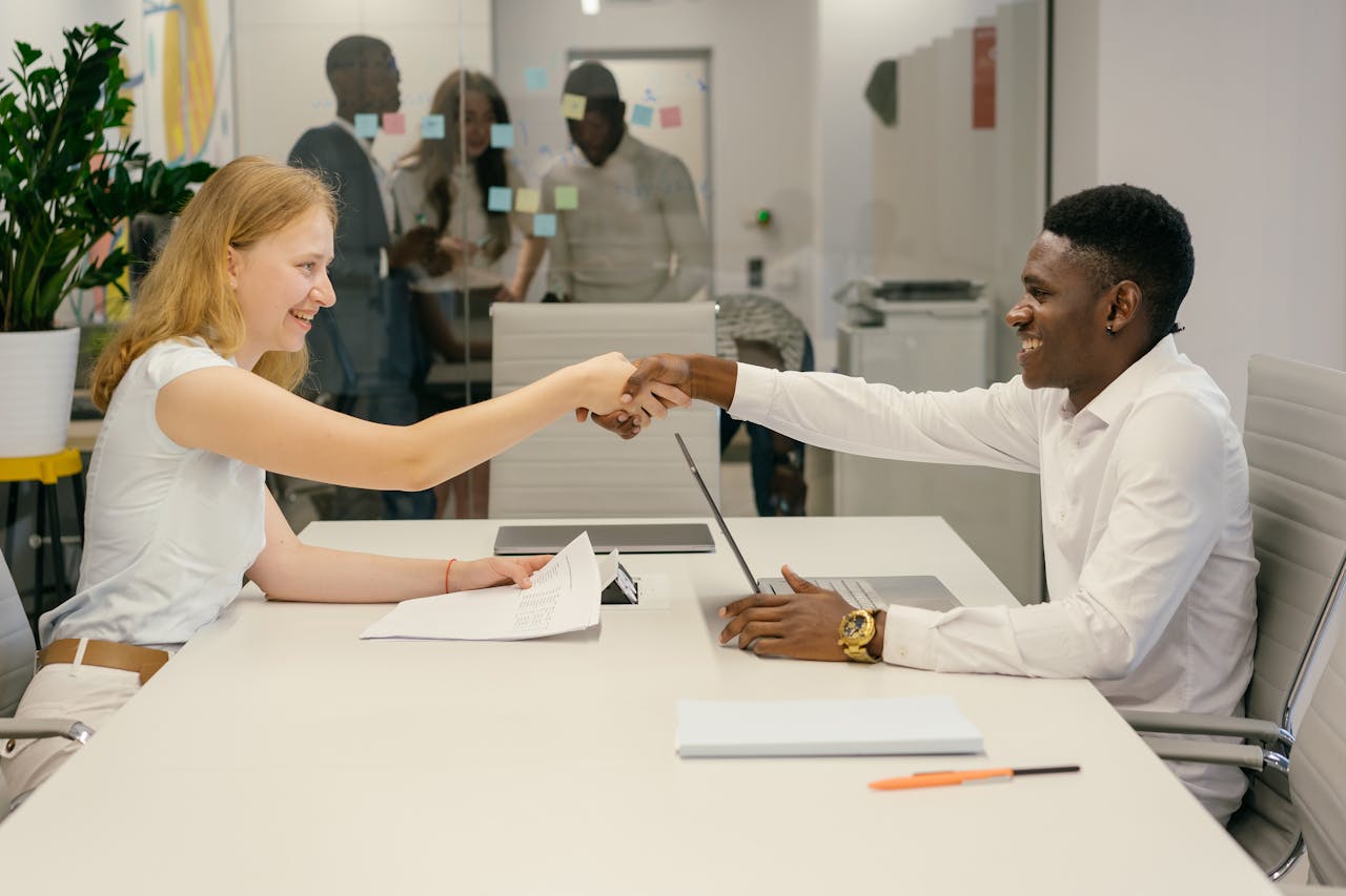 Business professionals completing a successful deal with a handshake in a modern office setting.